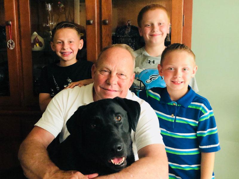 Heart disease survivor Gary Saunders in a 2018 photo with his grandsons (from left: Jaxon, Austin and Jaden Banks) and black lab Hunter. (Photo courtesy of Gary Saunders)